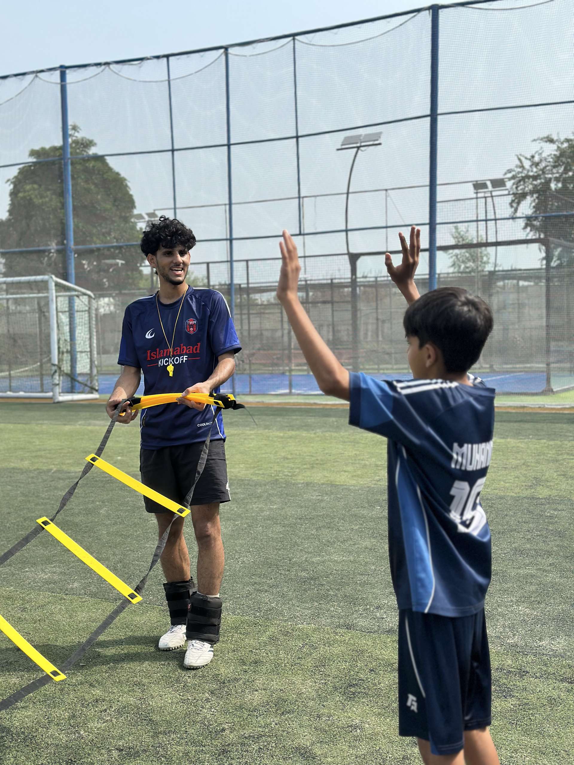 A TWA FC coach high-fiving a player at the end of a session