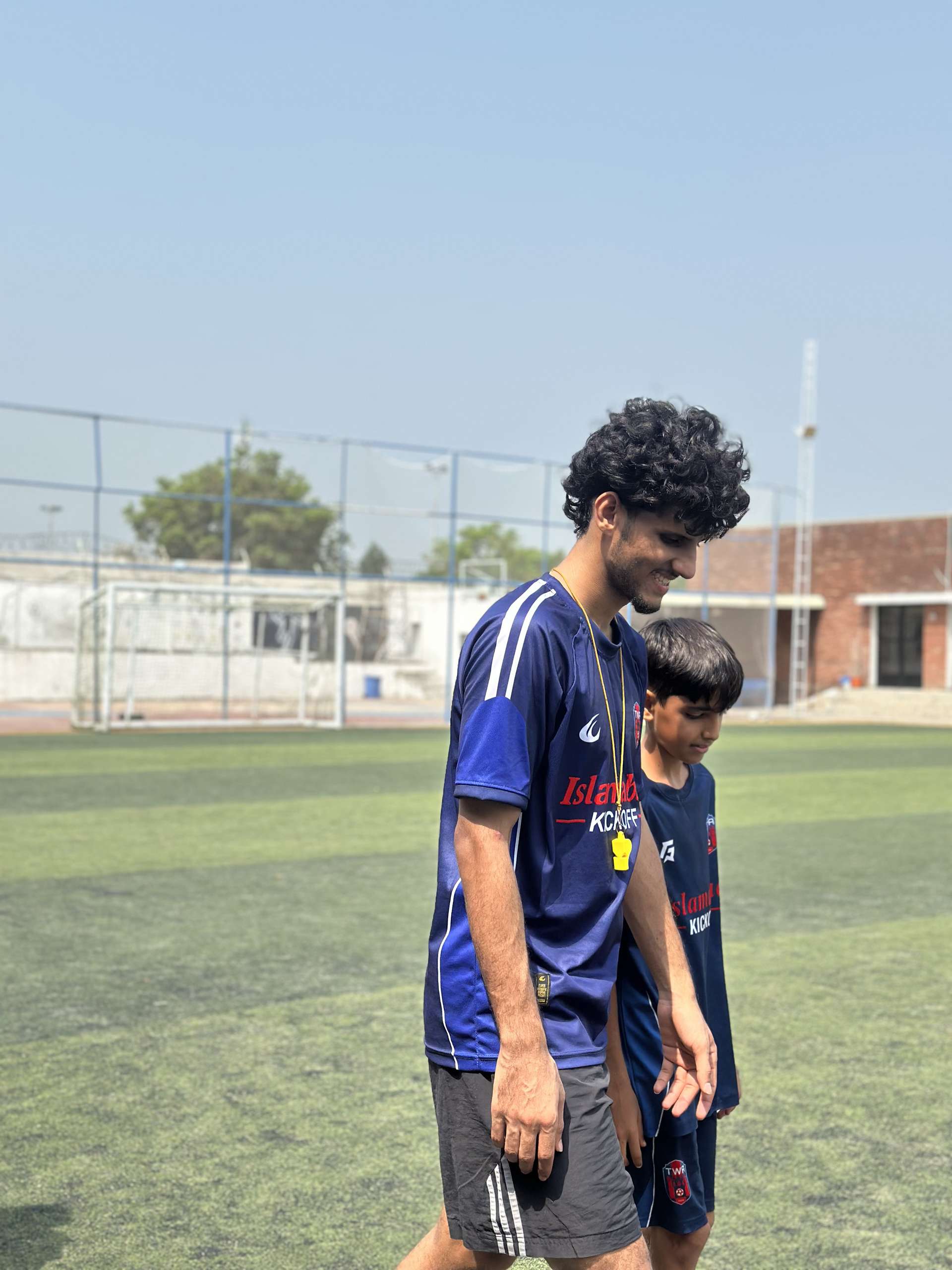 A coach walking off the pitch with the youngest player in the group
