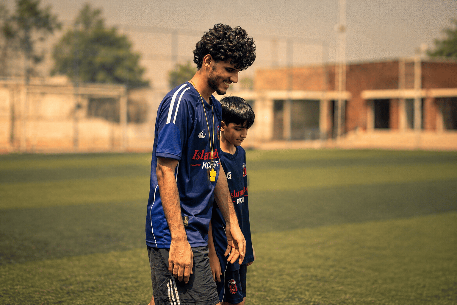 A TWA FC coach crouching to talk to one of the youngest players during training