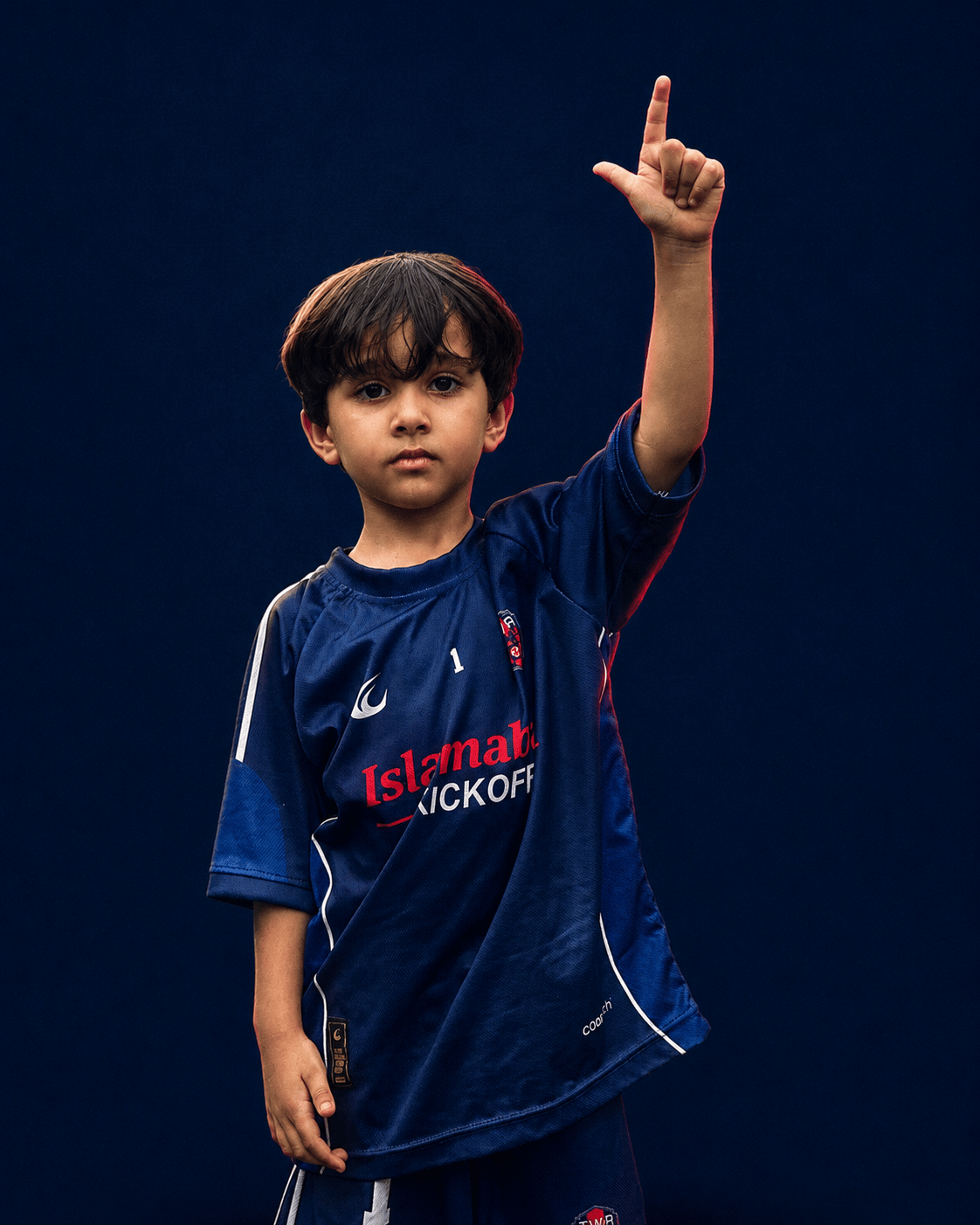 A U12 TWA FC player standing on a navy ground with the ball under his arm