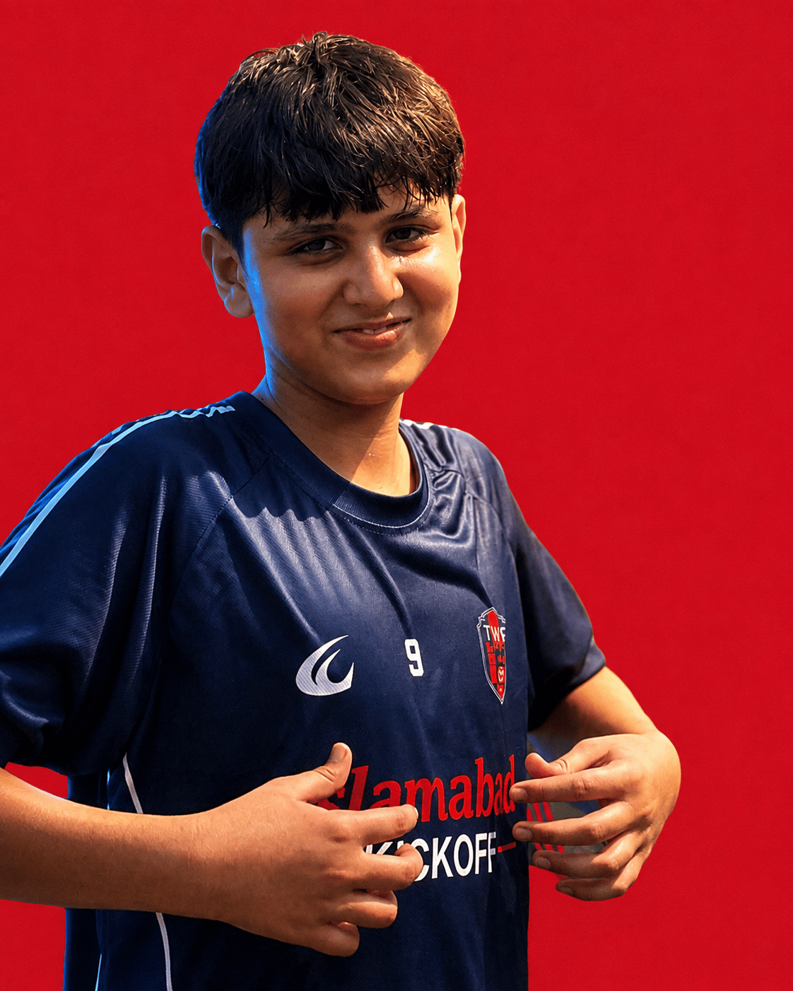 A U14 TWA FC player on a crimson ground, mid-stride in the home shirt