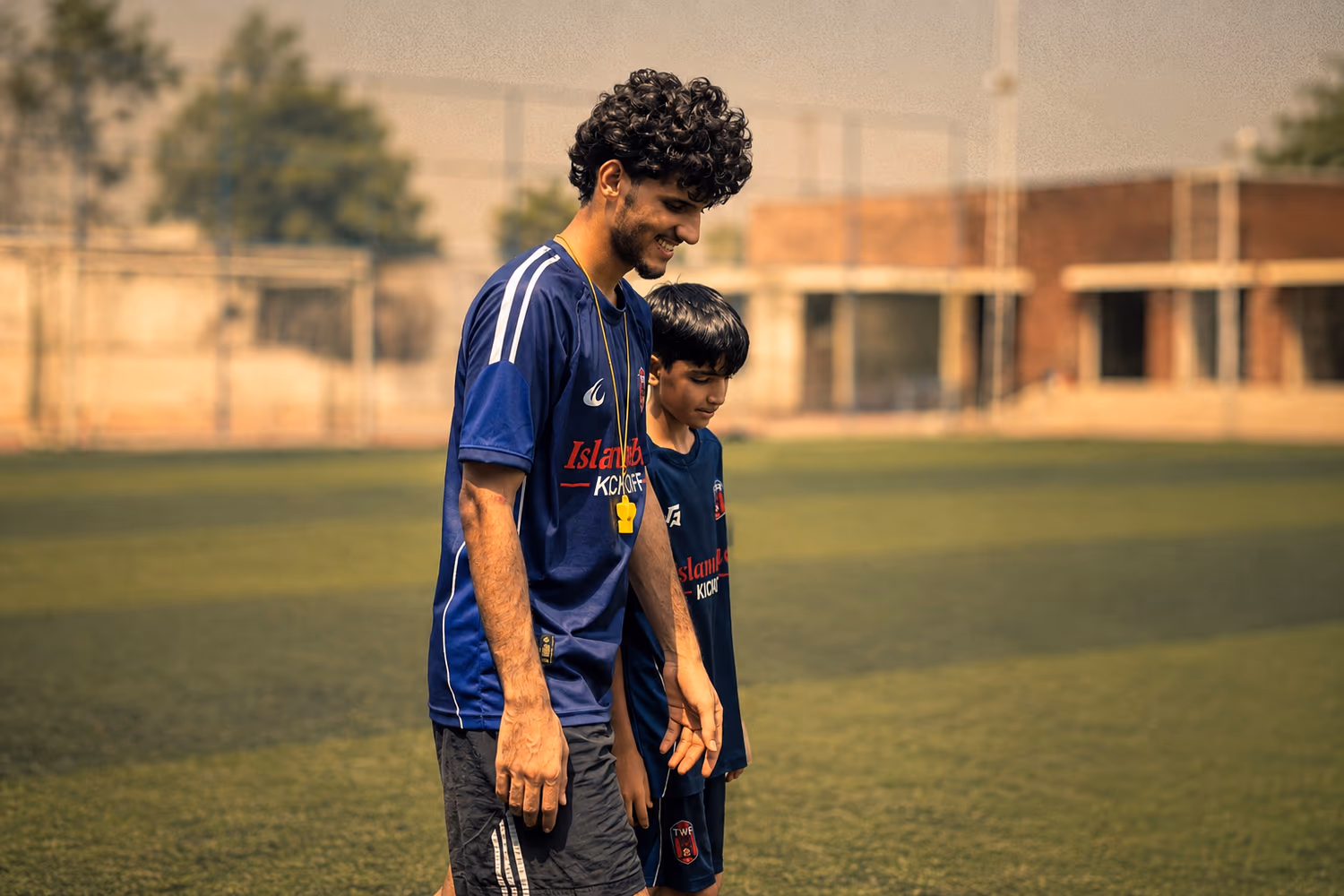 A TWA FC coach crouching to talk to one of the youngest players during training