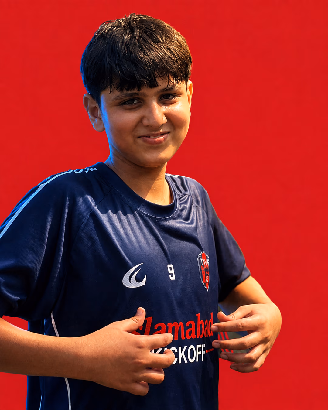 A U14 TWA FC player on a crimson ground, mid-stride in the home shirt