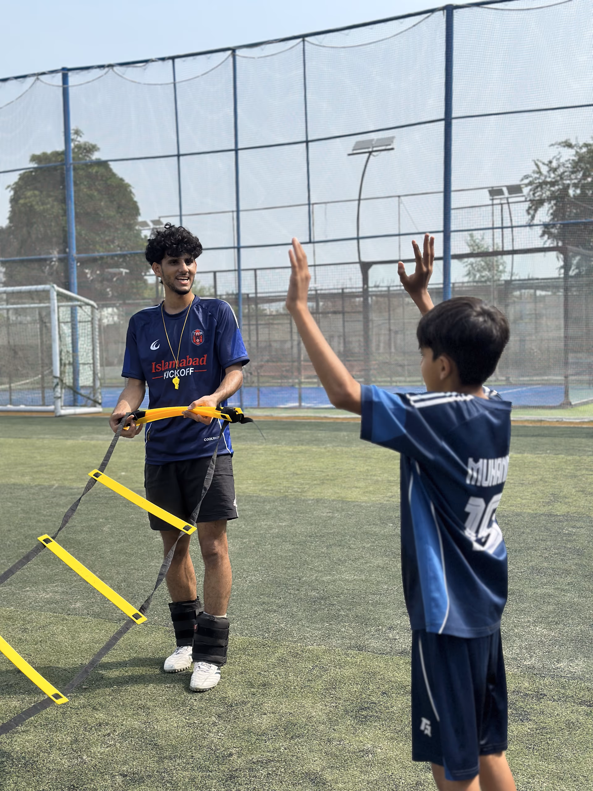 A TWA FC coach high-fiving a player at the end of a session