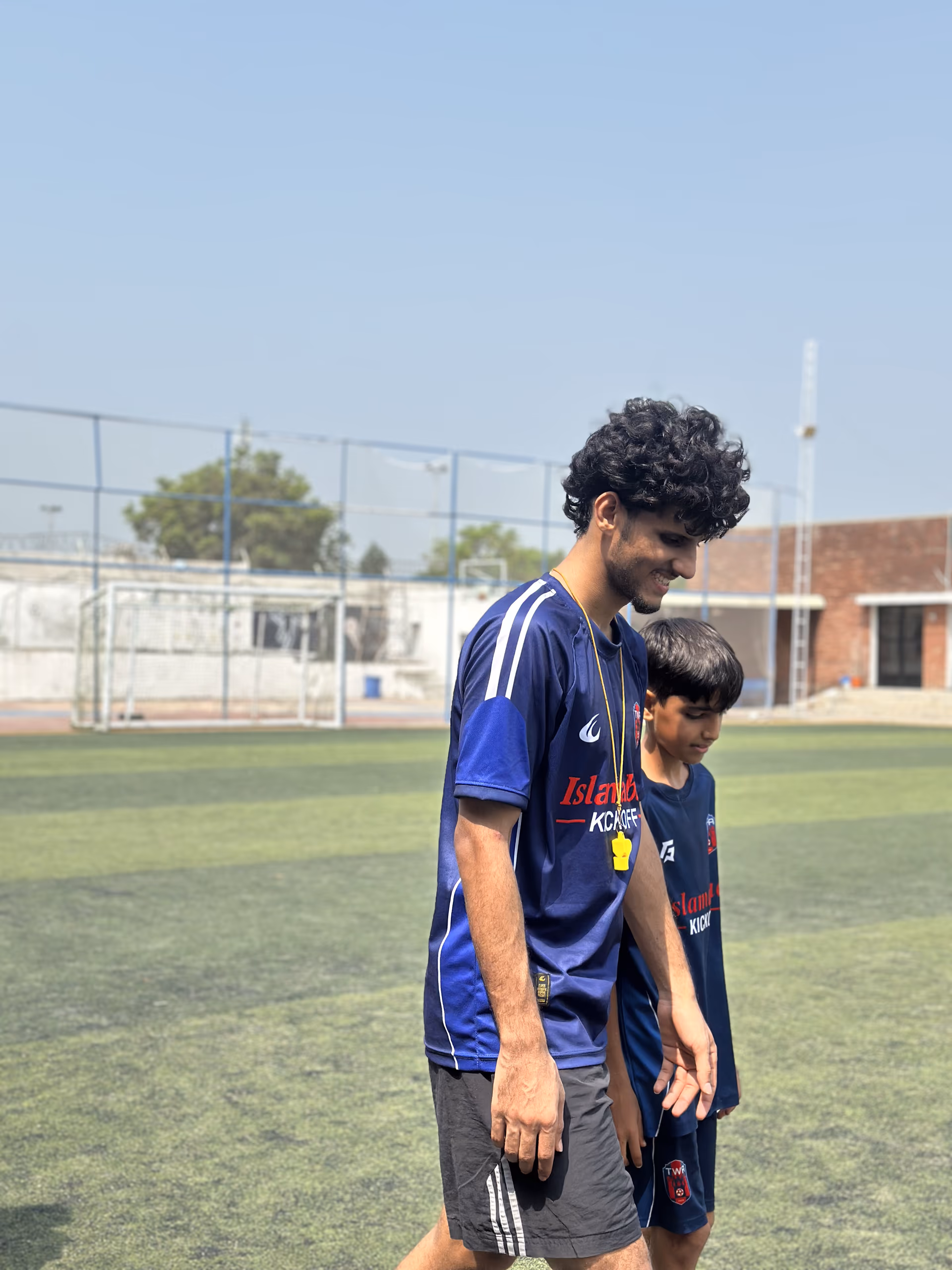 A coach walking off the pitch with the youngest player in the group